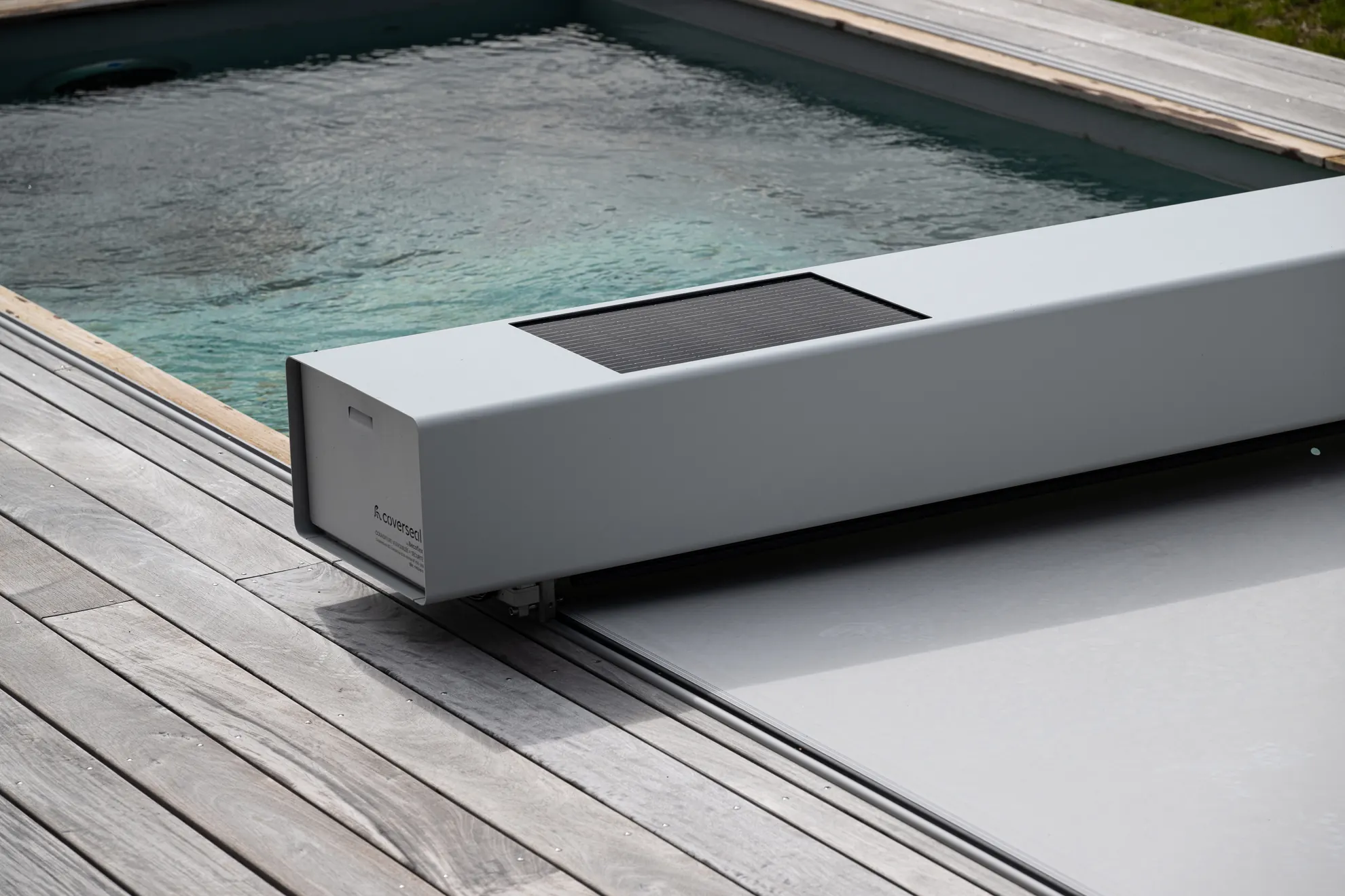 Couverture de piscine Coverseal gris clair installé en bord de piscine, avec membrane déployée.